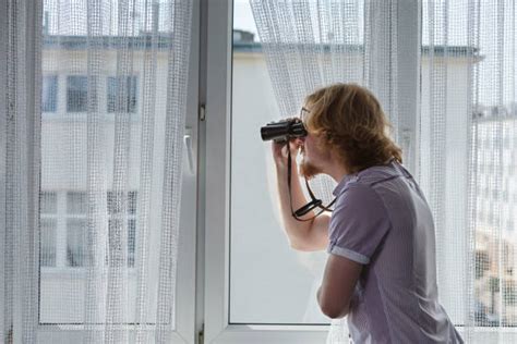 Man spying through window with binoculars